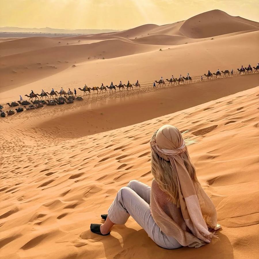 Vista aérea de dunas con caravana de camellos